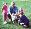 Bob holds the rooster  while three children take a look at it.